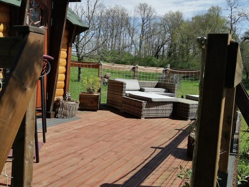 Charmante cabane en bois avec terrasse ensoleillée et mobilier confortable.