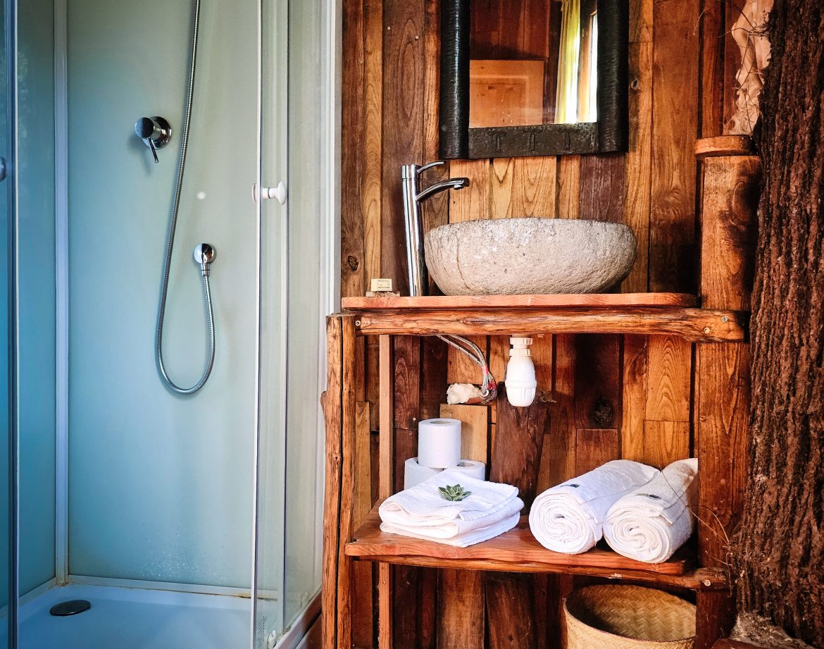 Hébergement insolite en Limousin : salle de bain en bois avec douche et lavabo en pierre.