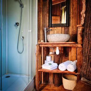 Hébergement insolite en Limousin : salle de bain en bois avec douche et lavabo en pierre.