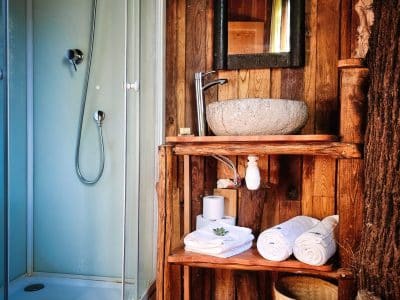 Hébergement insolite en Limousin : salle de bain en bois avec douche et lavabo en pierre.