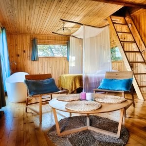 Hébergement insolite en bois à Limousin, avec baignoire sur pieds et coin salon cosy.