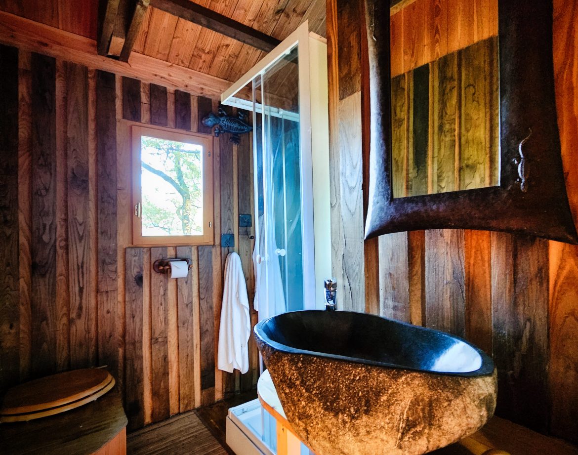 Cabane en bois à Limousin avec douche moderne et lavabo en pierre. Ambiance chaleureuse.