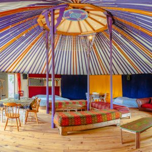 Yourte colorée en Basse-Normandie, avec un intérieur chaleureux et des lits confortables.