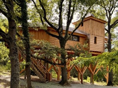 Cabane perchée en bois, entourée darbres verdoyants à Midi-Pyrénées.