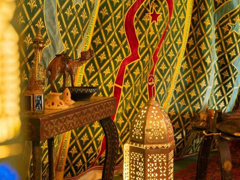 Tente berbère décorée, avec des lanternes et un camelot en bois. Ambiance chaleureuse.