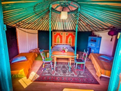 Yourte colorée en Basse-Normandie, décorée avec des tapis et des meubles artisanaux.