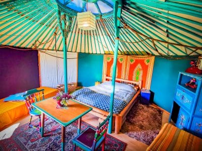 Yourte colorée en Basse-Normandie, avec un lit douillet et des décorations vibrantes.