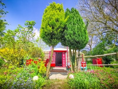 Cabane insolite en Basse-Normandie, entourée de verdure et de fleurs colorées.