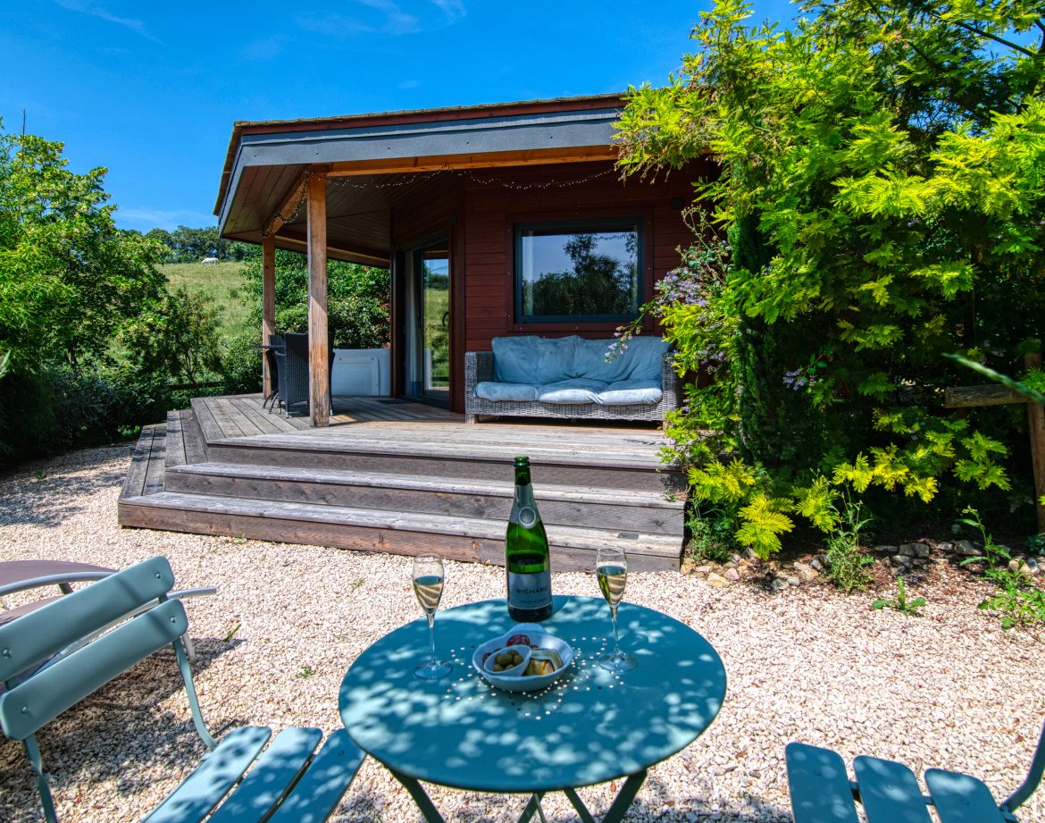 Cabane en bois à Languedoc-Roussillon, avec terrasse et verdure environnante.