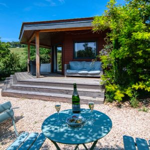 Cabane en bois à Languedoc-Roussillon, avec terrasse et verdure environnante.