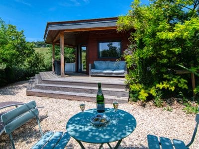 Cabane en bois à Languedoc-Roussillon, avec terrasse et verdure environnante.