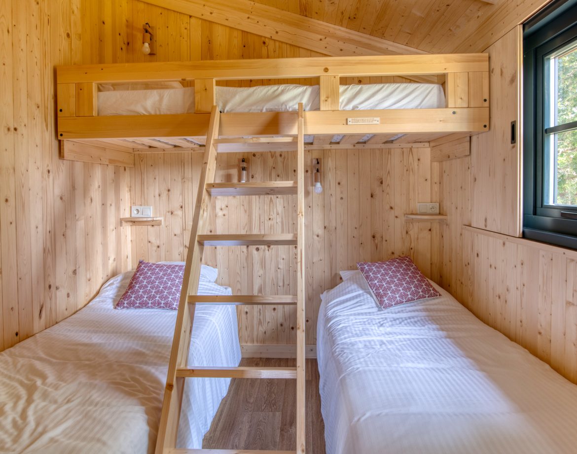 Cabane en bois avec lits jumeaux et mezzanine, ambiance chaleureuse et naturelle.