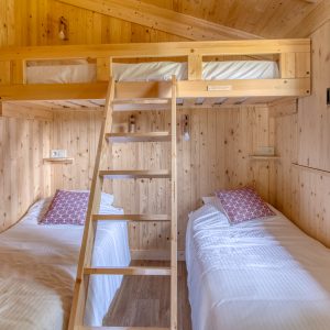 Cabane en bois avec lits jumeaux et mezzanine, ambiance chaleureuse et naturelle.