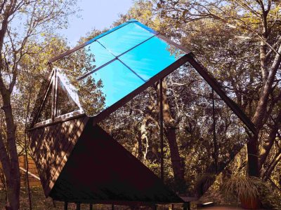 Cabane moderne en bois avec un toit en verre, nichée parmi les arbres.