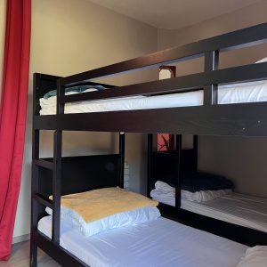 Chambre partagée avec lits superposés, murs clairs et rideaux rouges en Bourgogne.