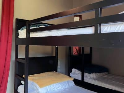 Chambre partagée avec lits superposés, murs clairs et rideaux rouges en Bourgogne.