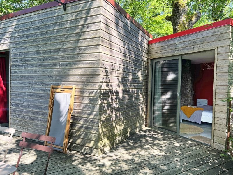 Cabane en bois moderne avec une vue sur un arbre majestueux. Terrasse en bois.