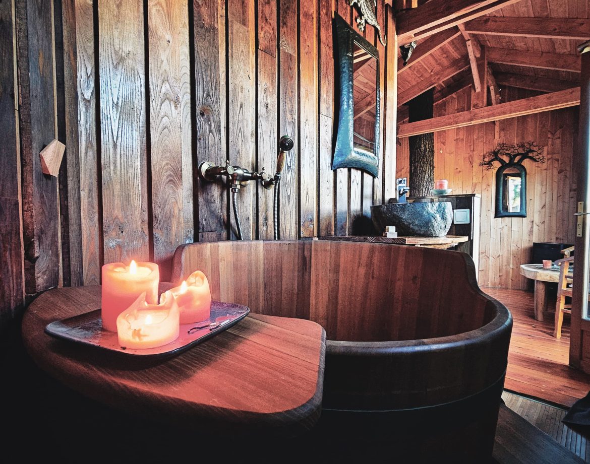 Hébergement insolite en Limousin : chalet en bois avec baignoire en bois et bougies.