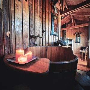 Hébergement insolite en Limousin : chalet en bois avec baignoire en bois et bougies.