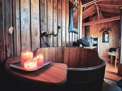 Hébergement insolite en Limousin : chalet en bois avec baignoire en bois et bougies.