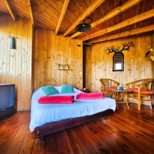 Cabane en bois cosy à Limousin, avec un lit douillet et des chaises en rotin.