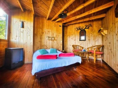 Cabane en bois cosy à Limousin, avec un lit douillet et des chaises en rotin.
