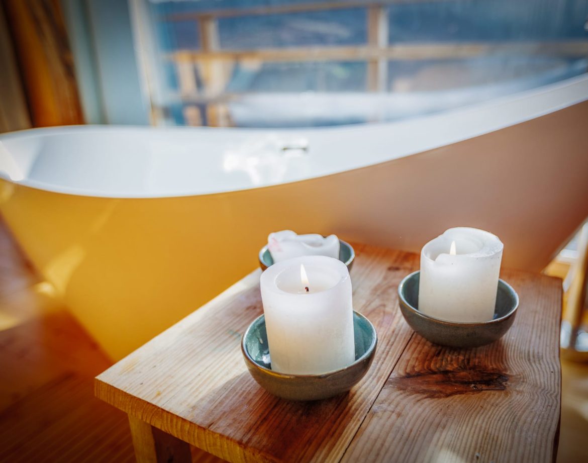 Hébergement insolite à Limousin : baignoire moderne avec bougies sur une table en bois.
