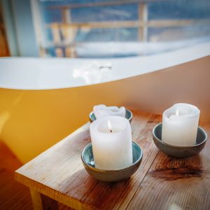 Hébergement insolite à Limousin : baignoire moderne avec bougies sur une table en bois.