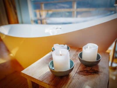 Hébergement insolite à Limousin : baignoire moderne avec bougies sur une table en bois.