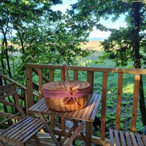 Cabane perchée en Midi-Pyrénées avec un panier pique-nique sur une terrasse en bois.
