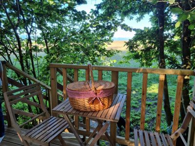Cabane perchée en Midi-Pyrénées avec un panier pique-nique sur une terrasse en bois.