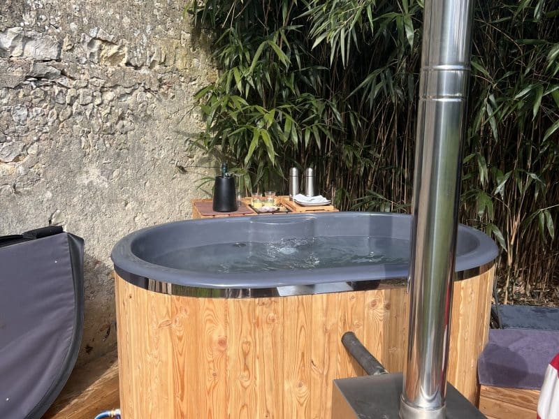 Bain nordique en bois, entouré de bambous, idéal pour une détente en pleine nature.