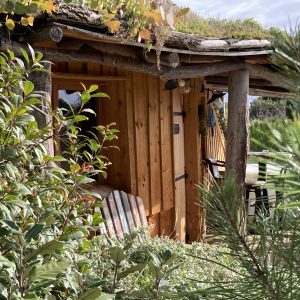 Cabane en bois avec toit végétal, entourée de verdure dans le Languedoc-Roussillon.