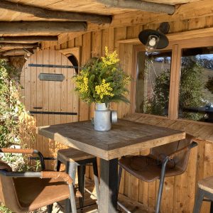 Cabane en bois à Languedoc-Roussillon avec table en bois et fleurs décoratives.