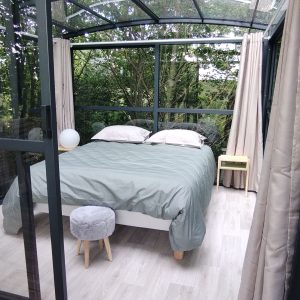 Chambre en verre suspendue, entourée de verdure, offrant une vue apaisante sur la nature.