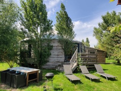 Yourte en bois à Basse-Normandie, entourée darbres et de chaises longues.