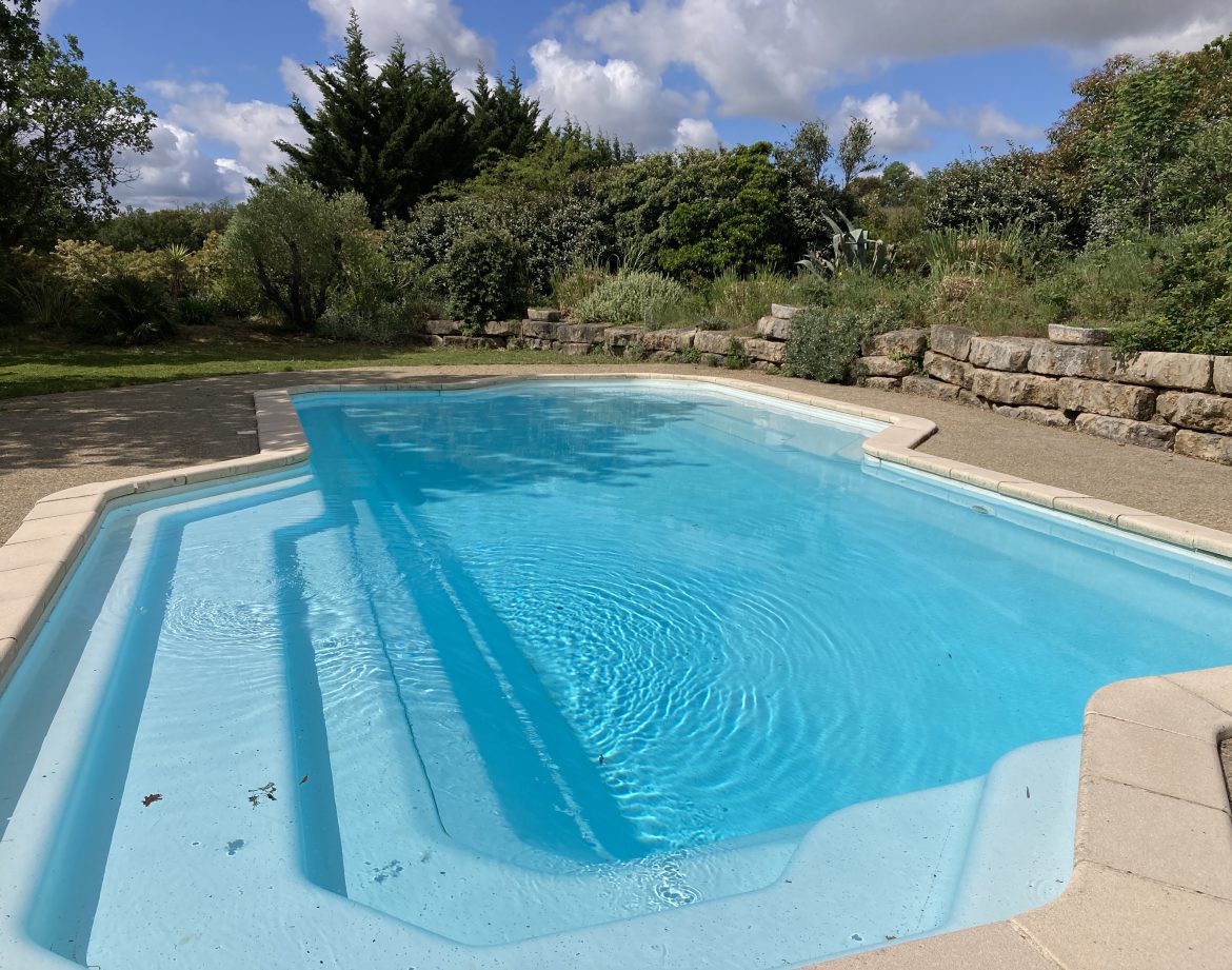 Hébergement insolite en Languedoc-Roussillon avec piscine turquoise et verdure environnante.