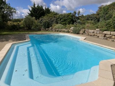 Hébergement insolite en Languedoc-Roussillon avec piscine turquoise et verdure environnante.