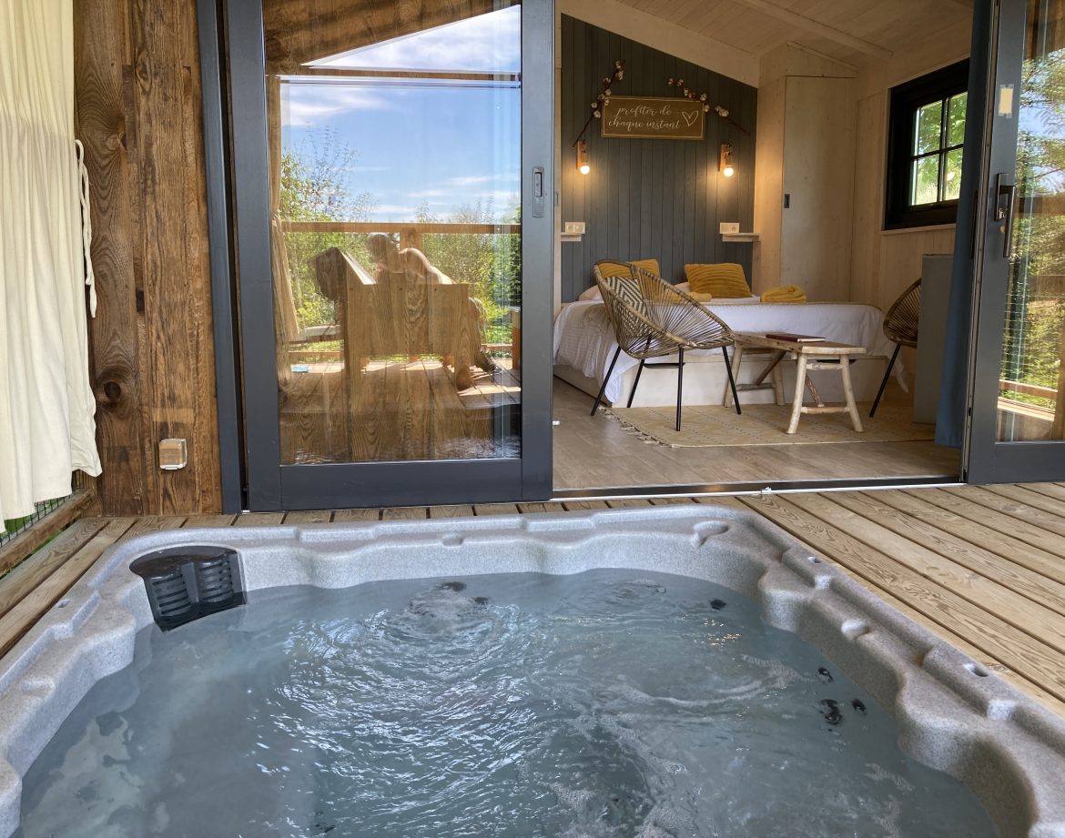 Cabane insolite avec jacuzzi, vue sur la nature et décoration chaleureuse.