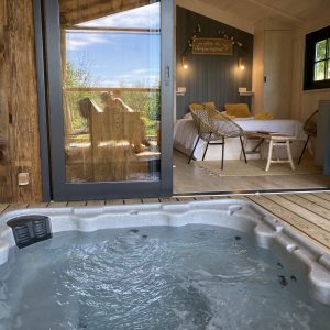 Cabane insolite avec jacuzzi, vue sur la nature et décoration chaleureuse.