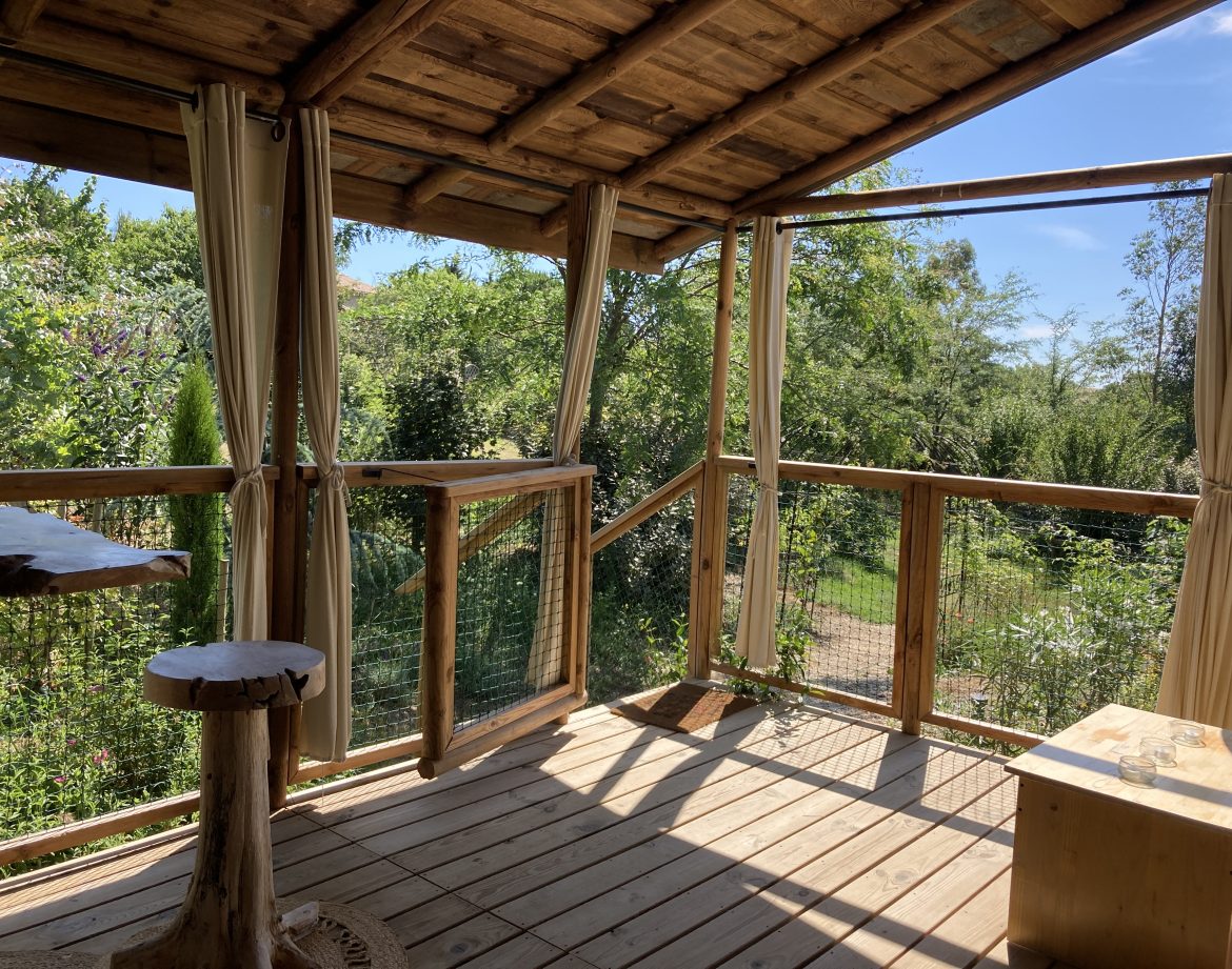 Cabane perchée en bois avec vue sur la nature verdoyante du Languedoc-Roussillon.