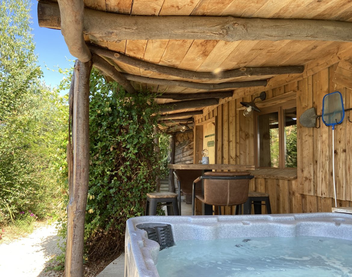 Cabane en bois avec jacuzzi, entourée de verdure dans le Languedoc-Roussillon.