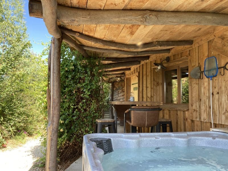 Cabane en bois avec jacuzzi, entourée de verdure dans le Languedoc-Roussillon.