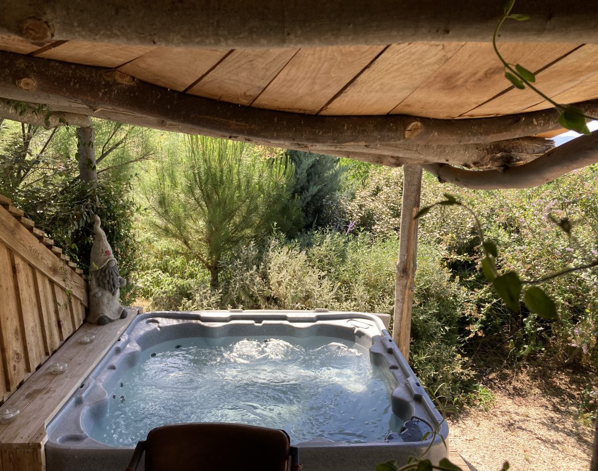Hébergement insolite en Languedoc-Roussillon avec jacuzzi sous un toit en bois naturel.
