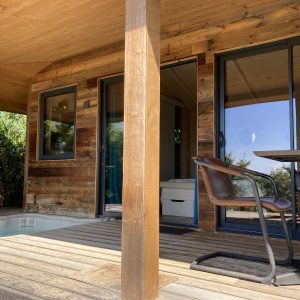 Cabane en bois avec terrasse et jacuzzi, entourée de verdure à Languedoc-Roussillon.