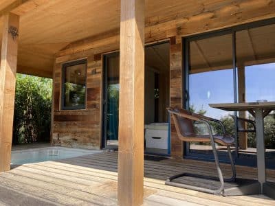 Cabane en bois avec terrasse et jacuzzi, entourée de verdure à Languedoc-Roussillon.