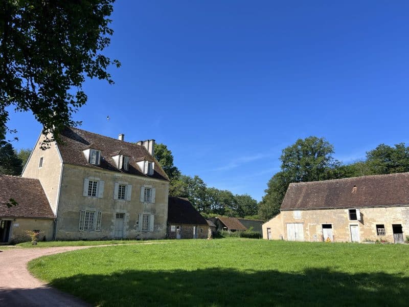 Charmante maison de campagne avec un grand jardin verdoyant sous un ciel bleu.