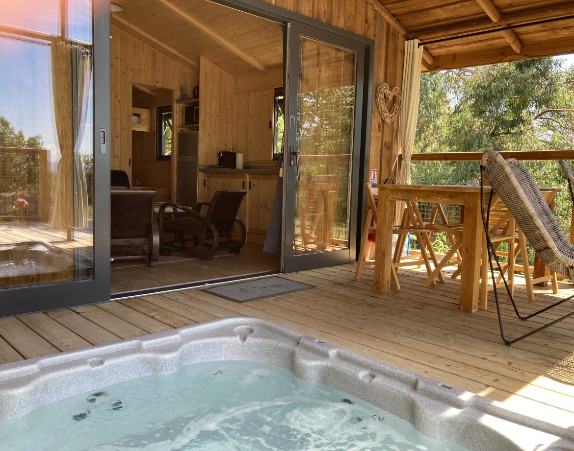 Cabane en bois avec jacuzzi sur la terrasse, vue sur la nature en Languedoc-Roussillon.