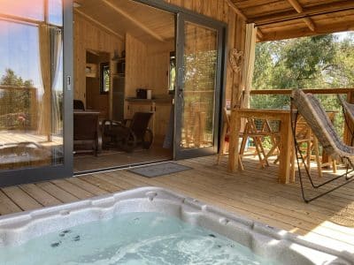 Cabane en bois avec jacuzzi sur la terrasse, vue sur la nature en Languedoc-Roussillon.
