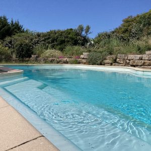 Hébergement insolite en Languedoc-Roussillon avec piscine turquoise entourée de verdure.